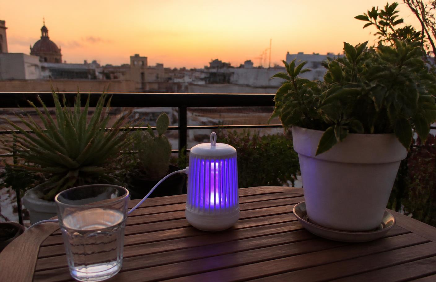 Mosquitron encendido sobre una mesa de terraza en un atardecer mediterráneo